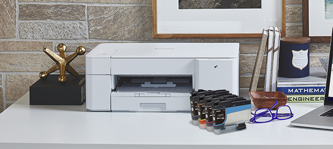 Brother's MFC-J1205W inkjet printer on a desk, with ink cartridges